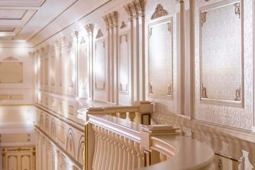 The interior of the event hall in a classic style with stucco on the walls and marble railings.