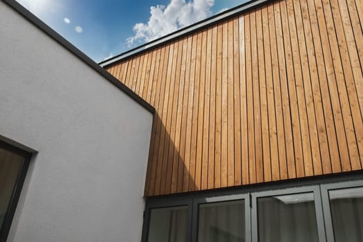 Exterior architectural detail of painted plaster and wood facade of modern buildings. The combination of different materials in the facade decoration.