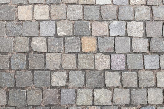 Background of natural stone paving stones laid in the ground, top view.