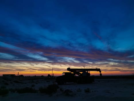 Silhouette of a Boom truck in the oilfield at sunset.