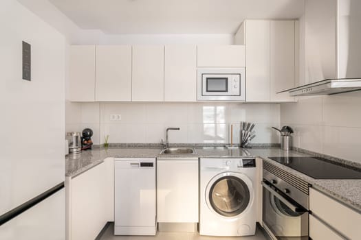 Bright stylish kitchen with modern appliances refrigerator, dishwasher and stove for cooking. The concept of a comfortable multifunctional kitchen after the delivery of the house.