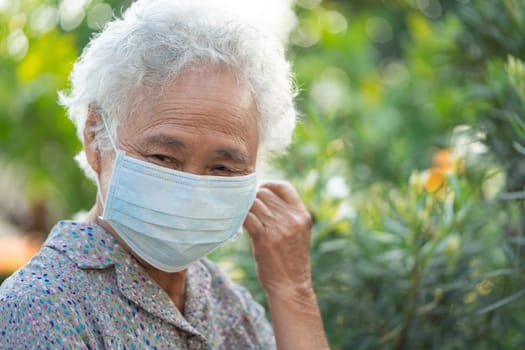 Asian elderly woman with face mask, fresh and happy in morning at park.