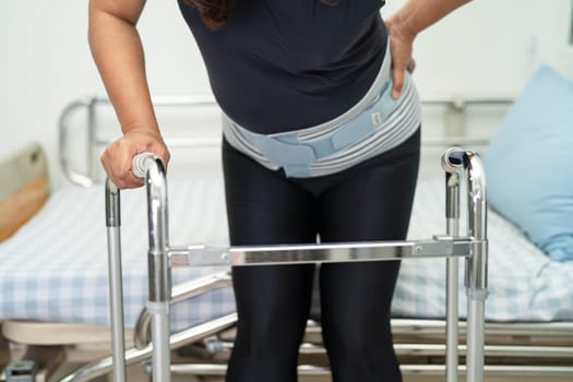 Asian lady patient wearing back pain support belt for orthopedic lumbar with walker.