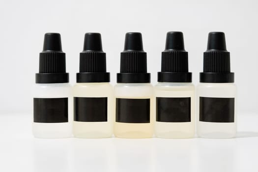 Set of plastic dropper bottles with liquid with black blank stickers. Mockup on white background with shadow