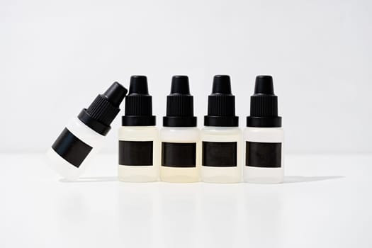 Set of plastic dropper bottles with liquid with black blank stickers. Mockup on white background with shadow