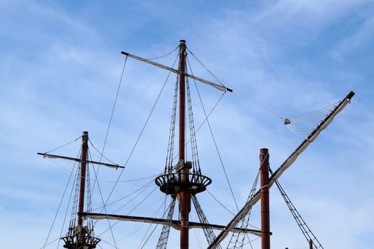 Masts of an ancient ship without sails against a cloudy sky close-up