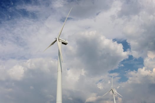 Two windmills of the power station against a cloudy sky view from below.