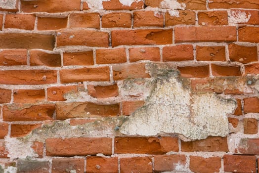 The wall is made of old ancient red brick. A brick wall badly damaged by time.