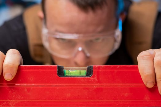 Quality control. Carpenter with spirit level checking the level of a plank of wood.