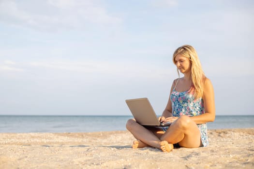 Beautiful young woman working with laptop on the tropical beach.