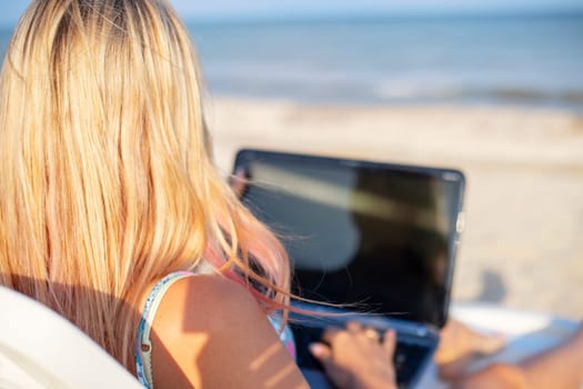 Beautiful young woman working with laptop on the tropical beach. Successful person concept.