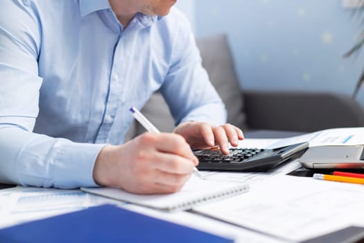 Man with bills and calculator. Businessman using calculator to calculate bills at the table in office. Financial accounting concept.