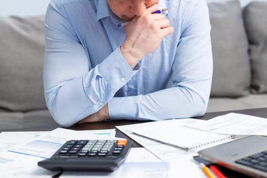 Distressed young man sit at desk paying bills feel stressed having financial problems. Unhappy upset male frustrated by debt or bankruptcy managing household budget or expenses.