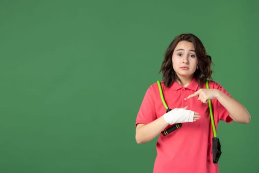 front view young pretty saleswoman with bandage on her hurt hand on a green background job injury health hospital color pain work