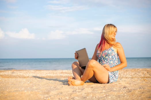 Beautiful young woman working with laptop on the tropical beach. Successful person concept.