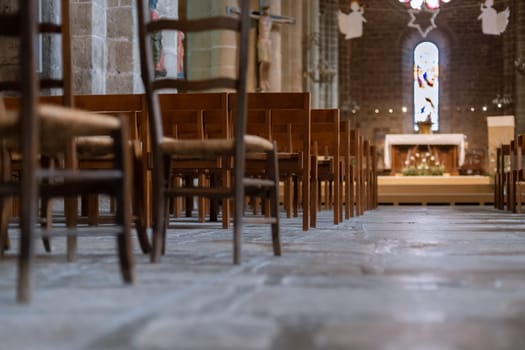 Row of wooden chairs inside in a church in France.