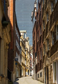 Narrow street of Lovat Lane in City of London with skyline dominated by skyscraper