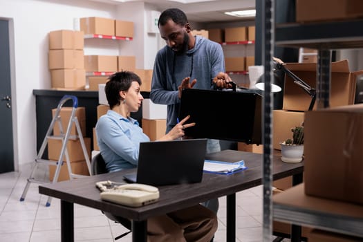 Storehouse manager holding metallic box while supervisor analyzing transportation order, discussing packaging production in warehouse. Team working at shipment logistic, checking distribution supply