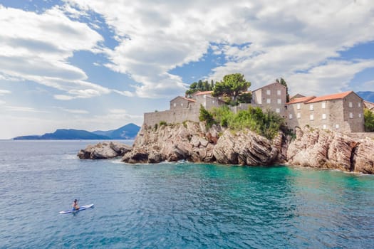 Young women Having Fun Stand Up Paddling in blue water sea near st stefan island in Montenegro. SUP.