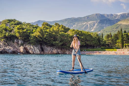 Young women Having Fun Stand Up Paddling in blue water sea near st stefan island against the backdrop of Milocer Park in Montenegro. SUP.