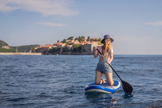 Young women Having Fun Stand Up Paddling in blue water sea near st stefan island in Montenegro. SUP.
