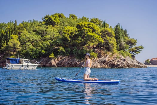 Young women Having Fun Stand Up Paddling in blue water sea near st stefan island in Montenegro. SUP.