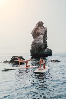 Woman sup yoga. Middle age sporty woman practising yoga pilates on paddle sup surfboard. Female stretching doing workout on sea water. Modern individual hipster outdoor summer sport activity