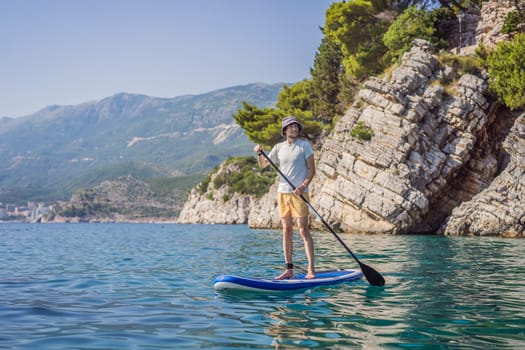 Young men Having Fun Stand Up Paddling in blue water sea near st stefan island against the backdrop of Milocer Park in Montenegro. SUP