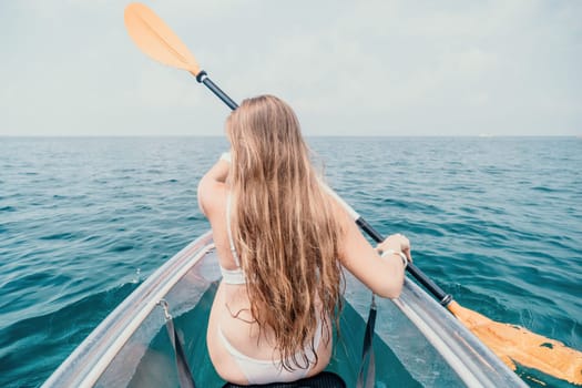 Woman in kayak back view. Happy young woman with long hair floating in transparent kayak on the crystal clear sea. Summer holiday vacation and cheerful female people having fun on the boat.