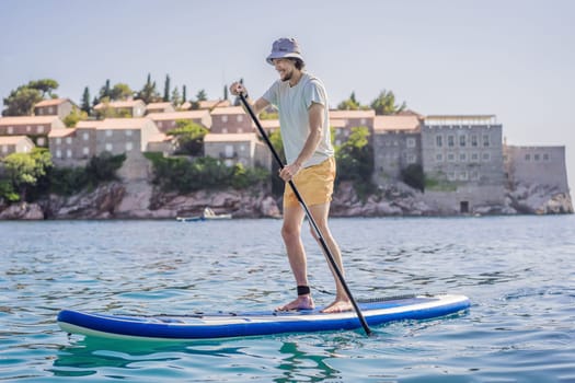 Young men Having Fun Stand Up Paddling in blue water sea near st stefan island in Montenegro. SUP.