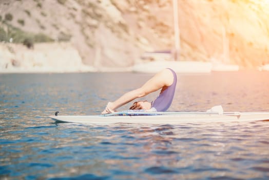 Woman sup yoga. Middle age sporty woman practising yoga pilates on paddle sup surfboard. Female stretching doing workout on sea water. Modern individual hipster outdoor summer sport activity