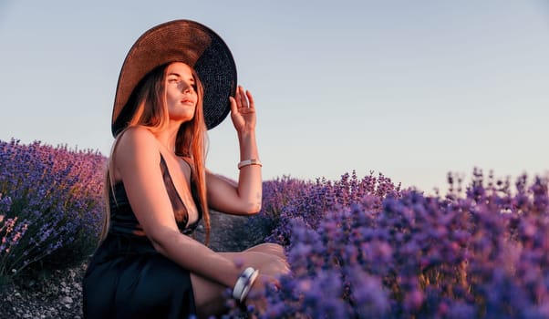 Close up portrait of young beautiful woman in a white dress and a hat is walking in the lavender field and smelling lavender bouquet.