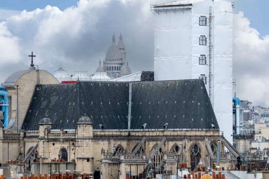 6 May 2023. Paris, France. Rooftop view of Paris preparing for the 2024 Olympics by remodeling, new construction. Telephoto shot with Sacre Coeur in the distance, church Saint Gervais and parts of Pompidou center in the foreground.