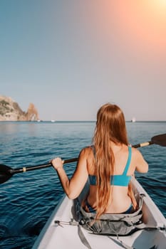 Woman in kayak back view. Happy young woman with long hair floating in transparent kayak on the crystal clear sea. Summer holiday vacation and cheerful female people relaxing having fun on the boat