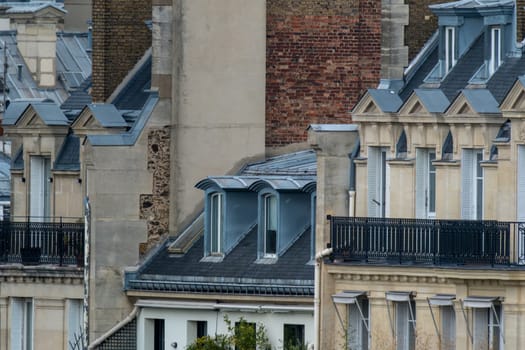 Close up roof top view of iconic Paris Haussmann apartment buildings showing balconies, zinc roof and dormers. High quality photo