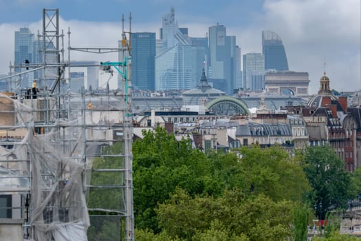 6 May 2023. Paris, France. Restoration and repair work continues in the city of Paris in preparation for the 2024 Olympics. Visible in the distance are La Defense district, the Grand Palais. Selective focus