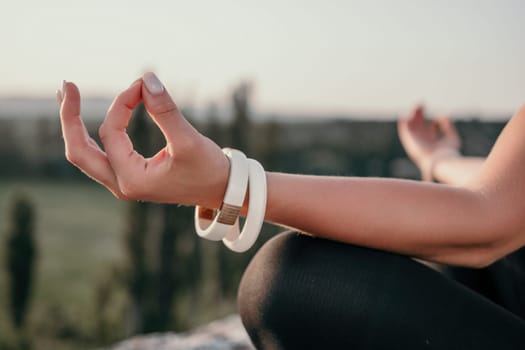 Well looking middle aged woman with long hair, fitness instructor in leggings and tops doing stretching and pilates on the rock near forest. Female fitness yoga routine concept. Healthy lifestyle.