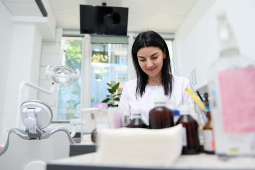 Portrait of a Caucasian beautiful woman, dentist orthodontist doctor in white medical coat, a confident experienced professional female prosthetic engineer working with dental mold at dentistry clinic