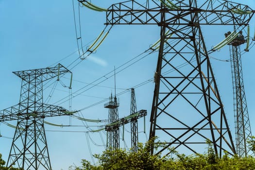 High voltage towers with sky background. Power line support with wires for electricity transmission. High voltage grid tower with wire cable at distribution station. Energy industry, energy saving.