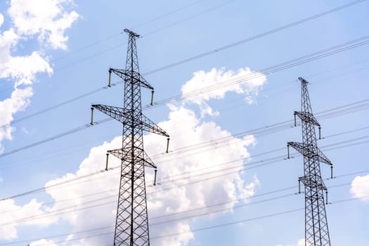 High voltage towers with sky background. Power line support with wires for electricity transmission. High voltage grid tower with wire cable at distribution station. Energy industry, energy saving.