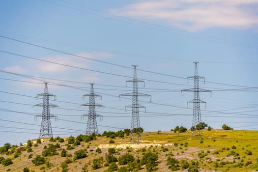 High voltage towers with sky background. Power line support with wires for electricity transmission. High voltage grid tower with wire cable at distribution station. Energy industry, energy saving.