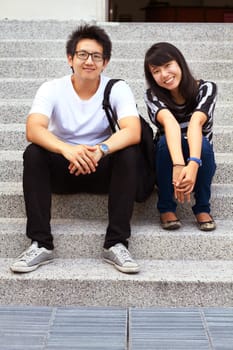 Portrait, education and an asian couple on steps, sitting outdoor at university together for learning. Love, study or college with a man and woman student on stairs to relax while bonding at break.
