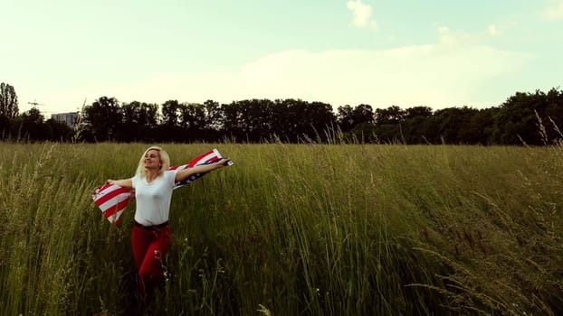 Young happy woman waving USA stars and stripes flag in golden sunset sunshine field.