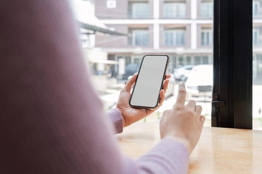 Woman sitting and holding blank screen mock up mobile phone.