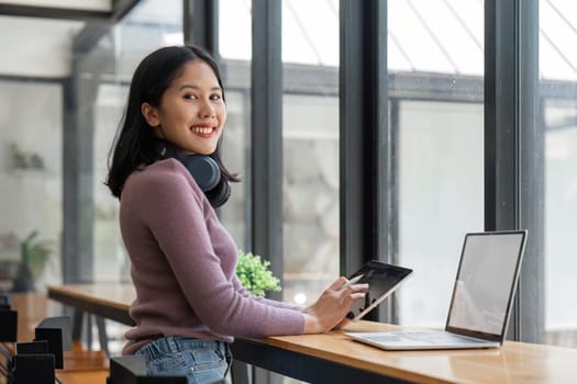 Smiling young teen girl and headphones studying on tablet. Happy pretty woman student looking at tablet and laptop screen watching.