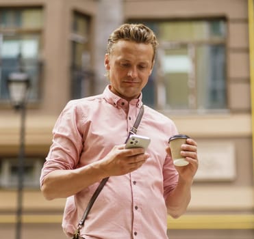 Mid-aged man texting message on phone. He enjoy cup of coffee from paper cup on summer city street. Intersection of technology, as man engages in mobile communication while enjoying coffee break. . High quality photo