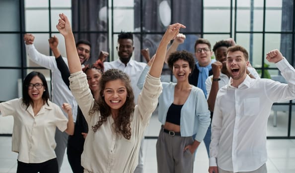 A team of young entrepreneurs and a startup raise their hands up celebrating their success