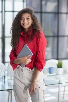 Elegant businesswoman standing in office with digital tablet
