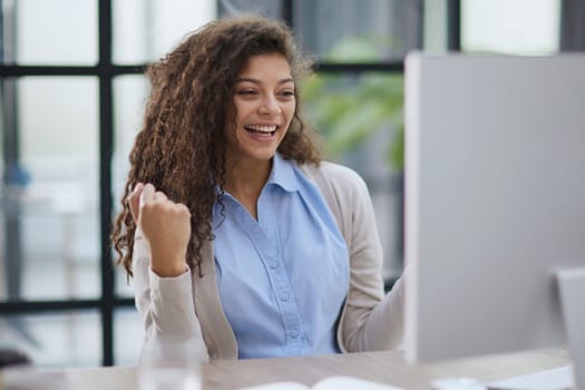 expressive young woman open mouth checking discounts for online shopping sitting at desktop .