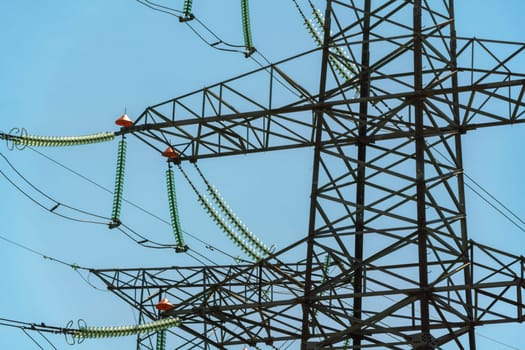 High voltage towers with sky background. Power line support with wires for electricity transmission. High voltage grid tower with wire cable at distribution station. Energy industry, energy saving.